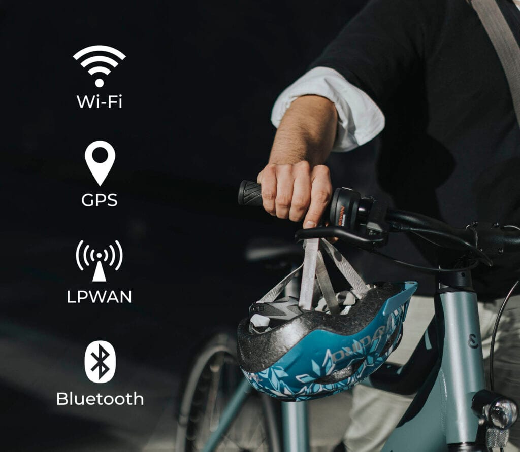 Person med sykkel og hjelm som viser BikeFinder sin avanserte sporingsenhet med GPS, Wi-Fi, LPWAN og Bluetooth-teknologi.